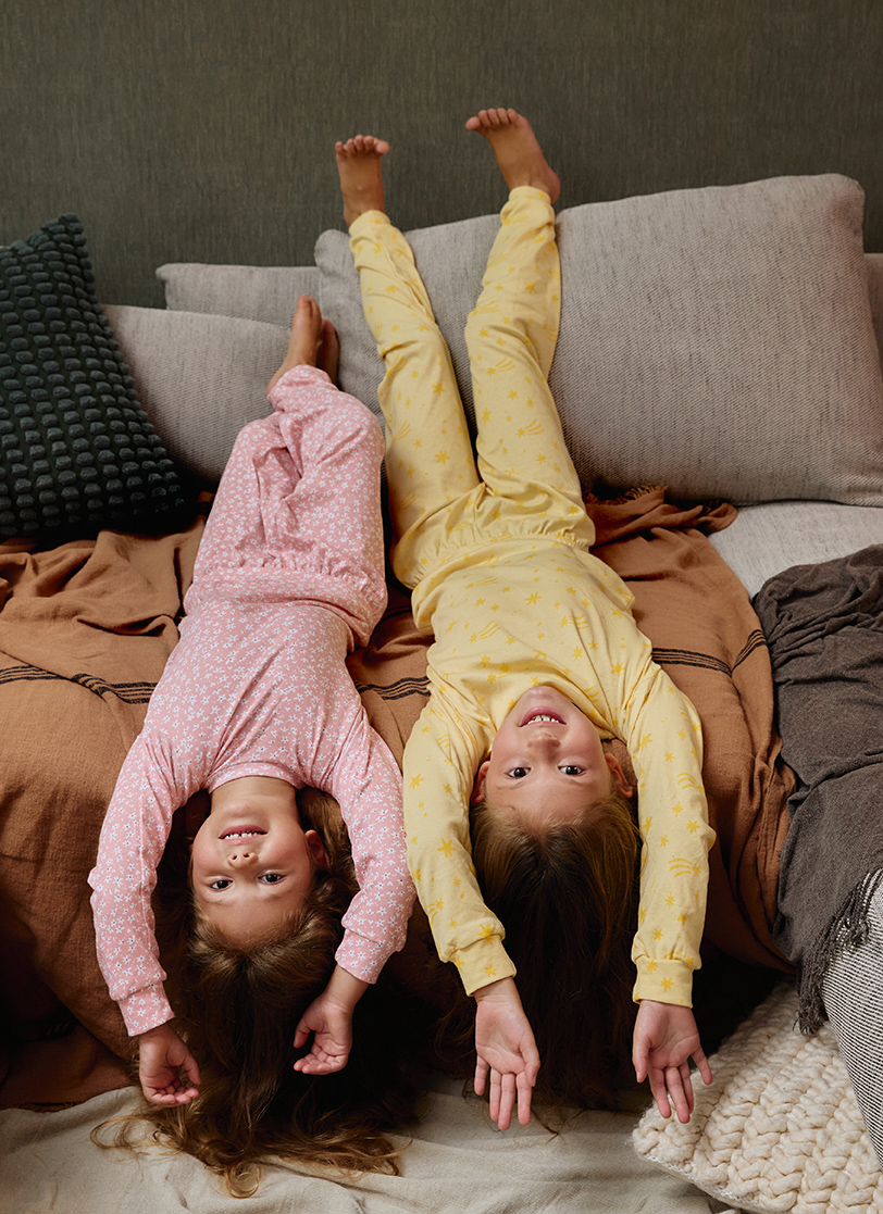 Dve djevojčice leže na krevetu sa pidžamama