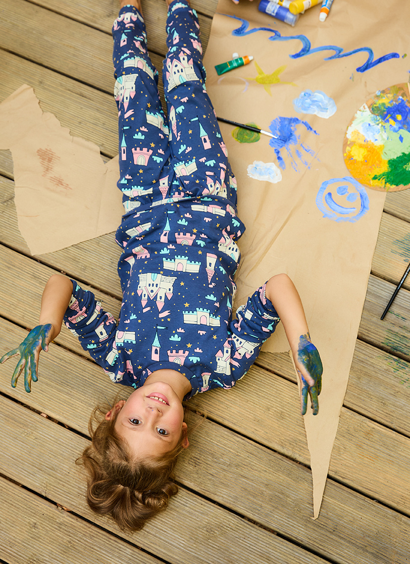 Djevojčica leži sa obojenim rukama u plavoj pidžami na dug rukav