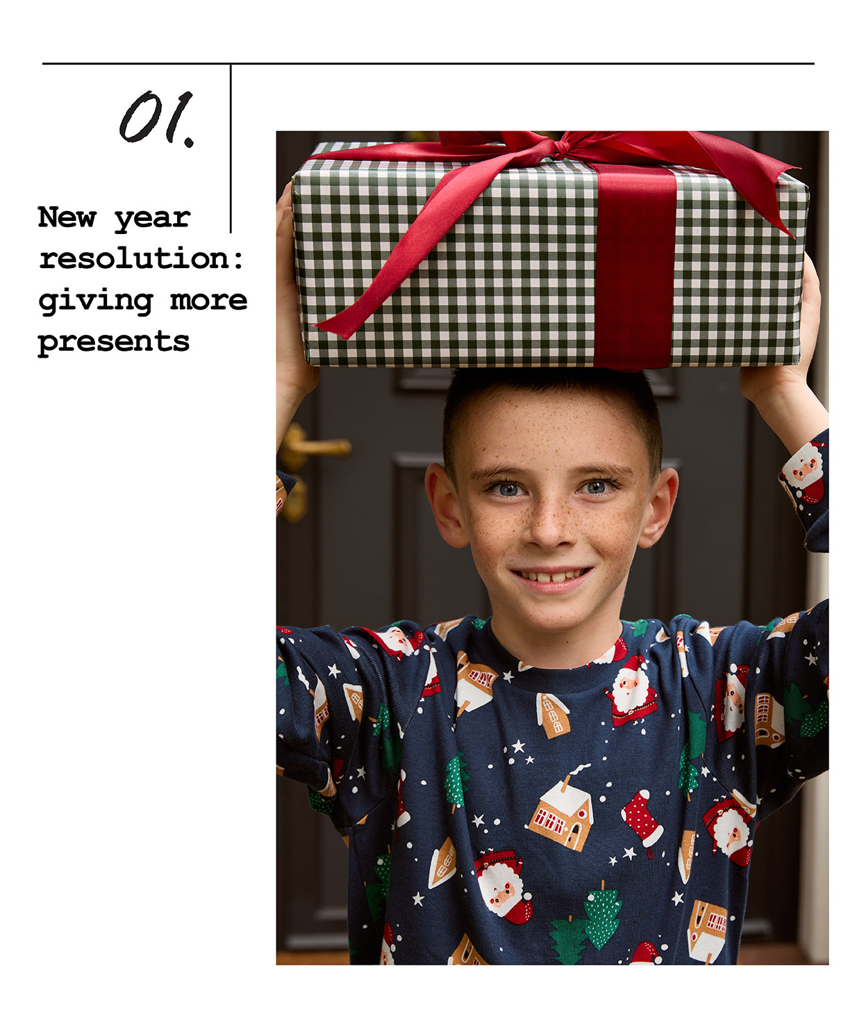 Dječak drži poklon iznad glave i nosi novogodišnju pidžamu