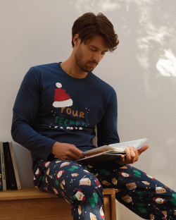 Muškarac u novogodišnjoj pidžami sedi i čita knjigu